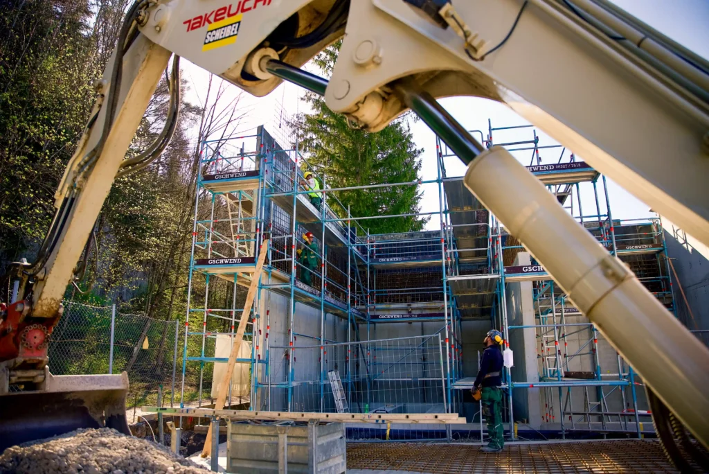 Bagger von Scheibel. Bauarbeiter im Hintergrund an Baustelle